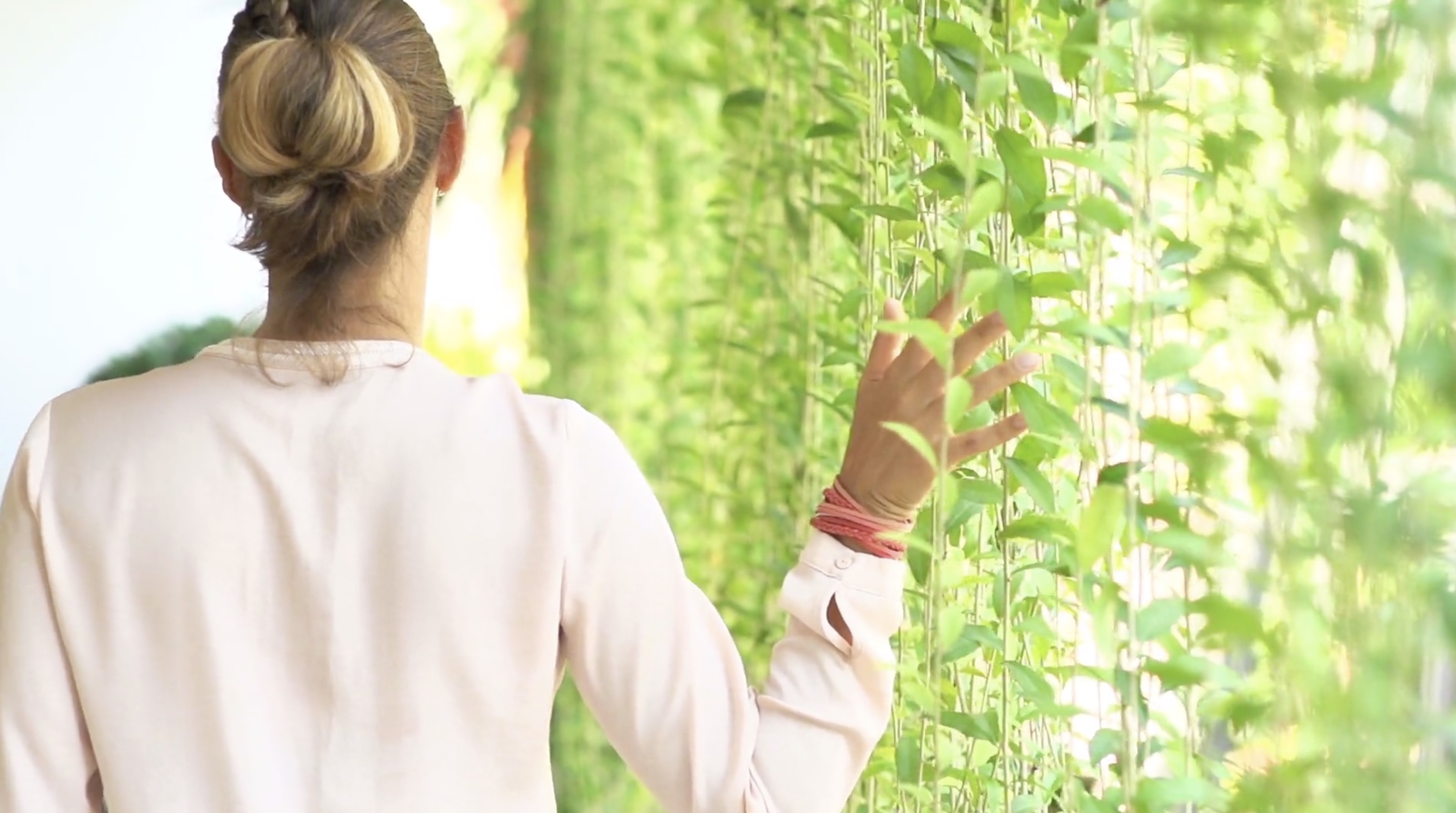 Young Woman Walking While Dragging Her Hand Along Hanging Vines