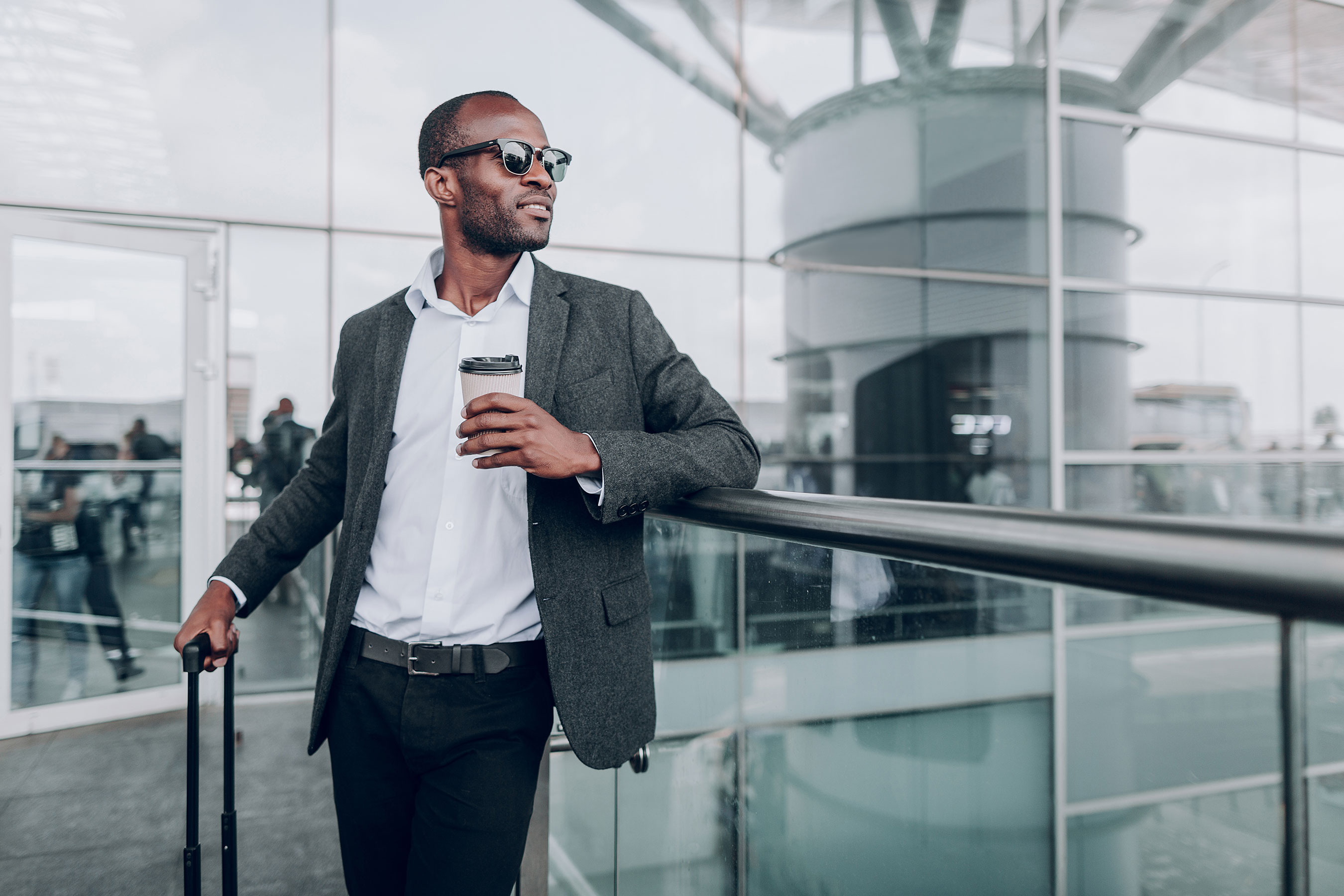 Man Wearing Sunglasses and Standing Next to Suitcase Looking Into the Distance